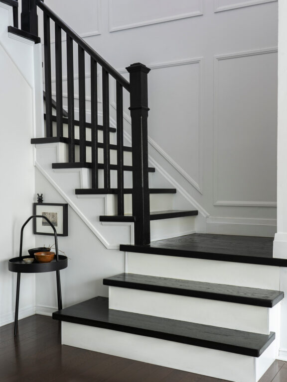 Modern home transformation by Toronto interior styling team If Walls Can Talk, featuring a striking black and white staircase, wood paneling, and curated decorative accents.